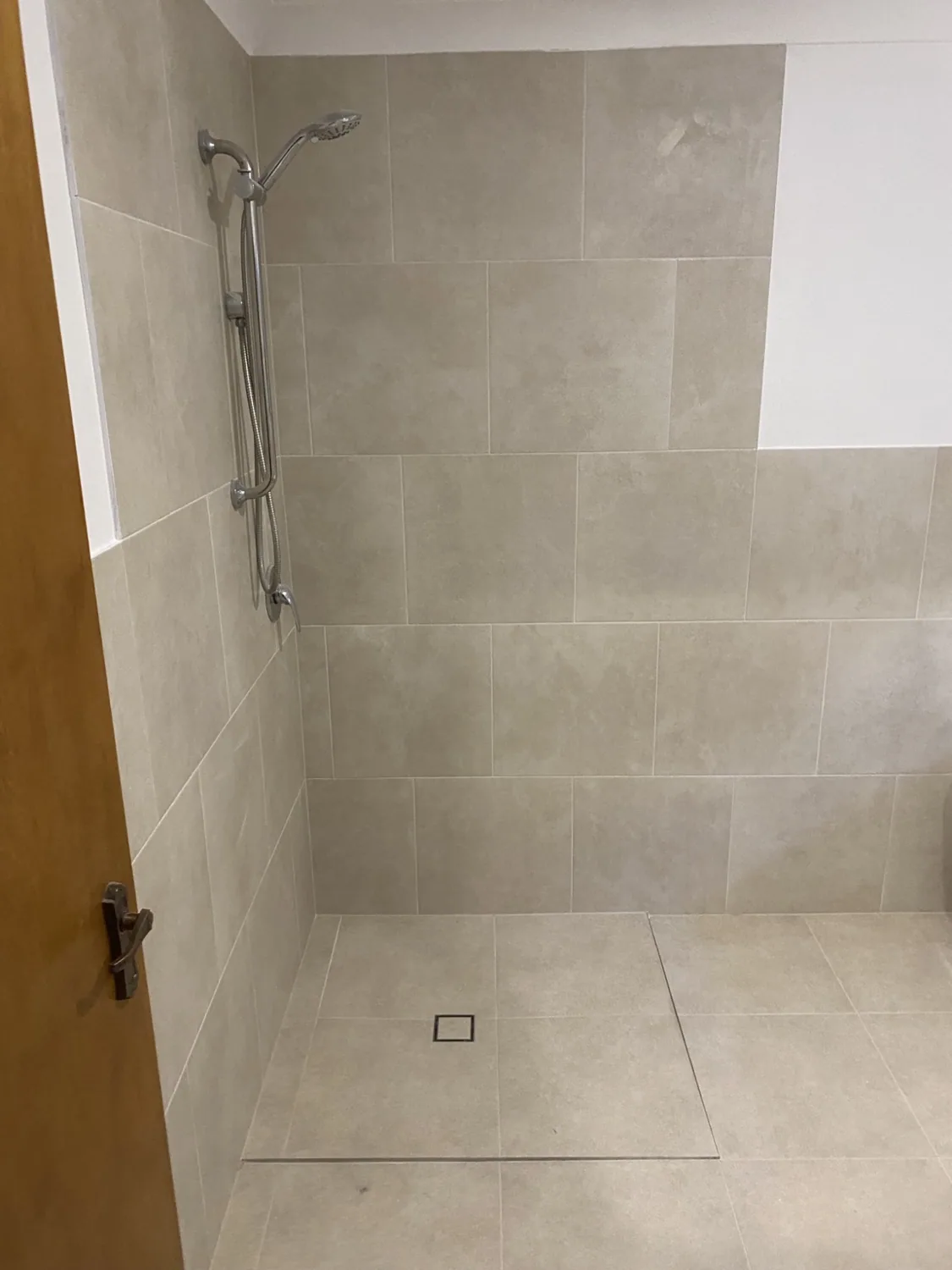 Completed tiled shower with handheld shower and floor waste