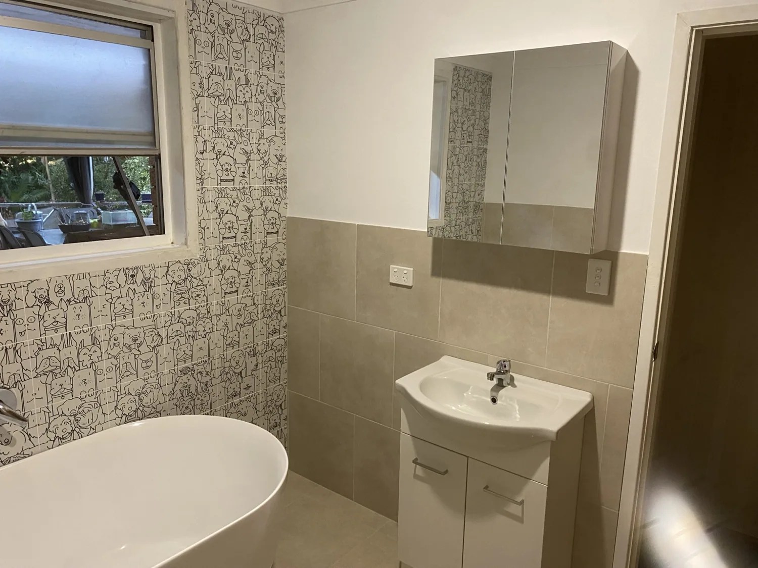 Completed bathroom with freestanding bath, vanity and feature wall tiles
